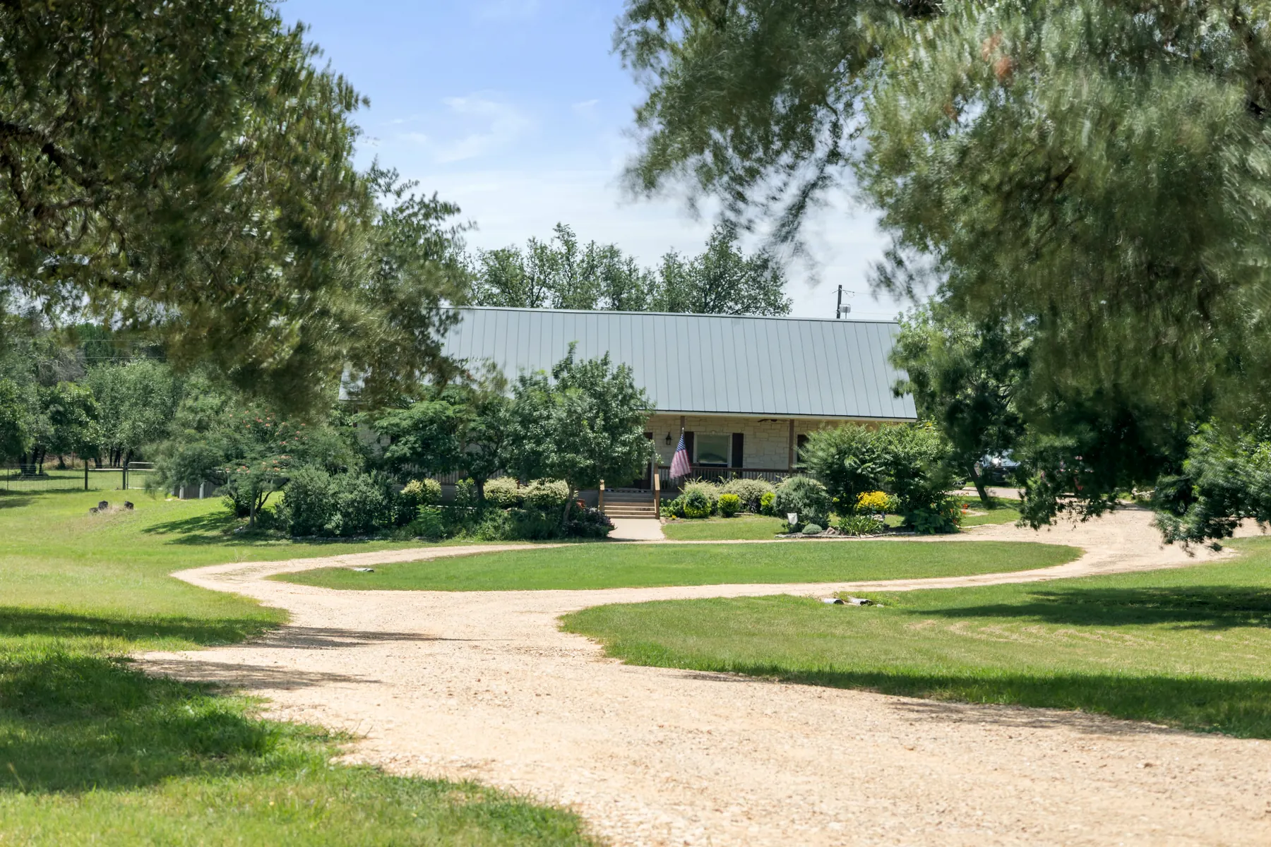 Tree-framed winding drive leading to a stone Hill Country home at 515 Liberty Dr